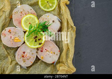 Frische Fischfilets aus Kongeraal, Zitronenkräuter, Pfeffer, Salz auf schwarzem Grund Stockfoto