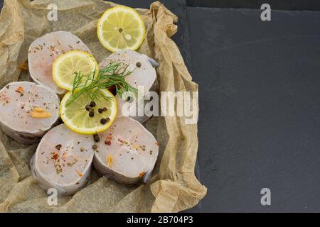 Frische Fischfilets aus Kongeraal, Zitronenkräuter, Pfeffer, Salz auf schwarzem Grund Stockfoto