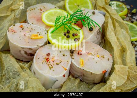 Frische Fischfilets aus Kongeraal, Zitronenkräuter, Pfeffer, Salz auf schwarzem Grund Stockfoto