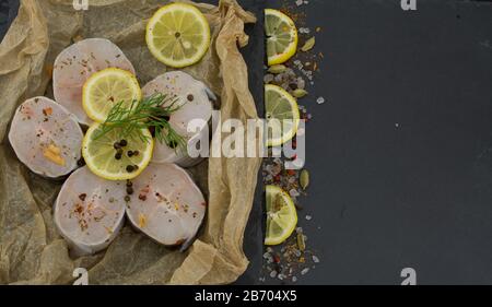 Frische Fischfilets aus Kongeraal, Zitronenkräuter, Pfeffer, Salz auf schwarzem Grund Stockfoto