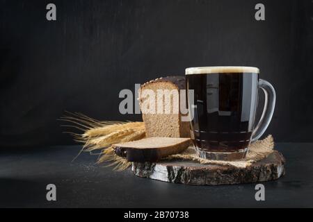 Russisches traditionelles Getränk fermentierter Kvass aus Roggenbrot im speziellen Halbliter-Becher auf dunklem Hintergrund. Kopierbereich. Stockfoto