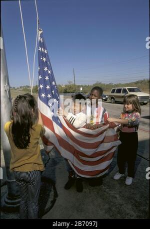 Austin, Texas, USA: Erstklässler, die am Morgen vor Beginn des Unterrichts auf dem Grundschulgelände die amerikanische Flagge hissen. HERR ©Bob Daemmrich Stockfoto