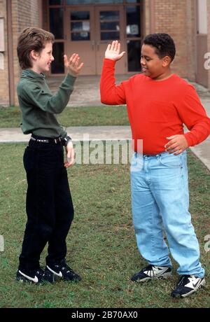 Austin, Texas, USA: Jungs der fünften Klasse machen auf dem Spielplatz „High Five“. HERR ©Bob Daemmrich Stockfoto