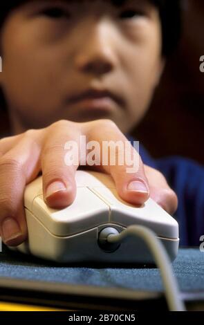 Austin Texas USA, 1998: Die Hand des asiatisch-amerikanischen Kindes greift die Computermaus, während er den Computer benutzt. HERR ©Bob Daemmrich Stockfoto