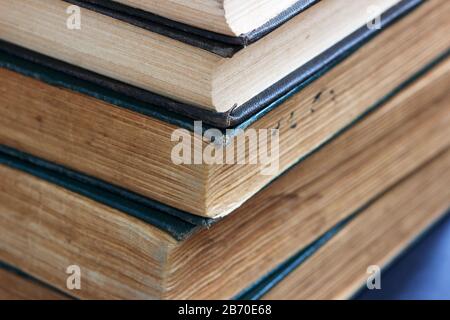 Alte Bücher mit ausgefransten Einbänden auf einem dunklen Tisch. Stockfoto