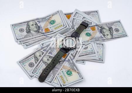 Armbanduhr liegt auf dem Hintergrund verstreuter US-Dollar Stockfoto