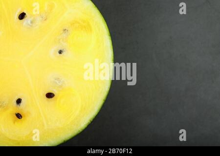 Halbe gelbe Wassermelone auf schwarzem Hintergrund, Textur des saftigen Fruchtfleischs reifer gelber Wassermelone Stockfoto