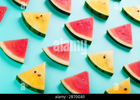 Scheiben frischer Scheiben mit gelber und roter Wassermelone auf blauem Hintergrund. Ansicht von oben Stockfoto
