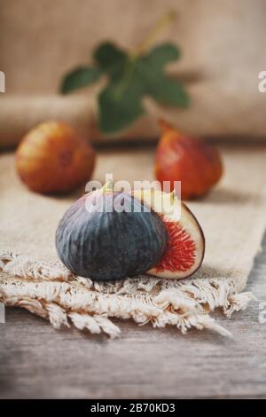 Feigen auf dem Tisch, Obstgruppe auf einem Holz-Bauerntisch mit Gratlappen. Feigenscheiben mit Fruchtfleisch. Gesundes und leckeres Obst Stockfoto