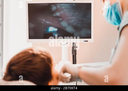 Ein junger Zahnmediziner untersucht die Zähne eines Jungen, der mit einer Zahnkamera in einem Zahnstuhl sitzt.2020 Stockfoto