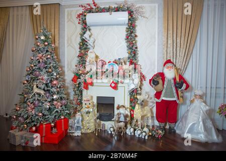 Nahaufnahme des dekorierten Weihnachtsbaums mit Geschenken darunter, Weihnachtsmannspielzeug, Spielzeughirsch und Stumpf, gezungtes Bild. Konzept von Frohe Weihnachten, Winter und Neu Stockfoto