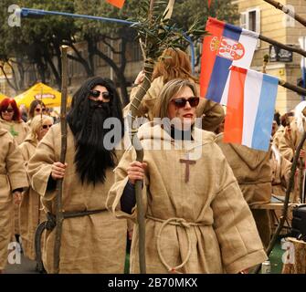 Rijeka, Kroatien, 23. Februar 2020. Mann und Frau maskiert als mittelalterlichen Priester Kostüme und in Jutekleidern mit großem Kruzifix auf der Brust gekleidet Stockfoto