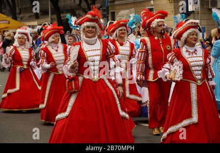 Rijeka, Kroatien, 23. Februar 2020. Fröhliche Gruppe von mittelalterlichen Damen in roten Krinolinenkleidern lächelnd und spazieren auf der Straße in attraktivem Kostüm Stockfoto