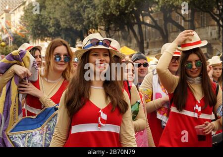 Rijeka, Kroatien, 23. Februar 2020. Fröhliche, lächelnde, fröhliche Mädchen und junge Frau mit Hüten und Brille, die im Karnevalszug der Straße spazieren gehen Stockfoto