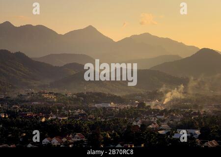 Blick auf die Stadt Luang Prabang, Laos, bei Sonnenuntergang, mit Bergen im Hintergrund. Stockfoto