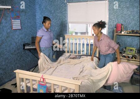 Austin Texas USA: Afroamerikanische Teenager-Schwestern machen sich zu Hause ein Bett. HERR ©Bob Daemmrich Stockfoto