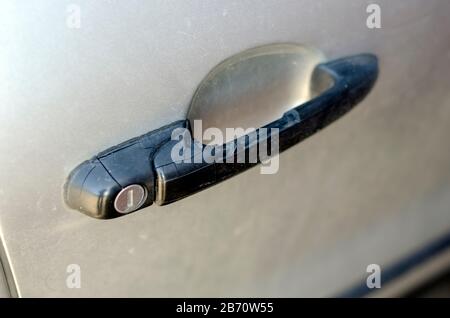 Gerissener Kunststoffgriff für die Autotür. Schwarzer Kunststoffgriff an der vorderen Tür der Limousine. Trockener Kunststoff. Nahaufnahme. Selektiver Fokus. Aufnahmen auf Augenhöhe. Stockfoto