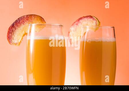 Sektecocktail Bellini in Kristallglas auf orangefarbenem Hintergrund. Nahaufnahme Stockfoto