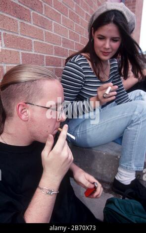 Austin Texas USA: High School Studenten schleicht sich draußen in einer abgelegenen Ecke des Schulcampus einen Rauch. ©Bob Daemmrich Stockfoto