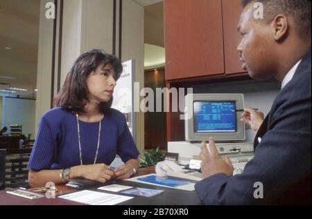 Austin Texas USA: Junger schwarzer Bankbeamter diskutiert bei der Bank mit weiblicher Kundin über Verbraucherkredite. HERR ©Bob Daemmrich Stockfoto