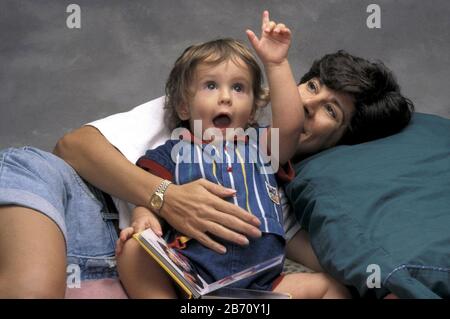 Austin Texas USA, 1995: Der 18 Monate alte Chris Daemmrich zeigt auf, als er mit seiner Mutter ein Buch anschaut. HERR ©Bob Daemmrich Stockfoto