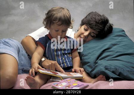 Austin Texas USA, 1995: 18 Monate alter Junge, der mit seiner Mutter ein Buch liest. HERR ©Bob Daemmrich Stockfoto