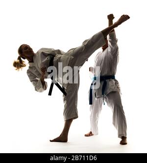 Zwei Mädchen in weißen Kimonos mit schwarzen und blauen Bändern, Training und Üben von Karate-Ständen und Techniken Stockfoto