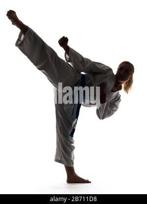 Karate Frau in Kimono gekleidet und posiert, während sie auf einem Bein steht. Foto in voller Länge auf weißem Hintergrund Stockfoto