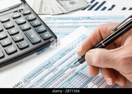 Der Mann füllt die Einkommenssteuererklärung aus. Formular 1040. Stockfoto