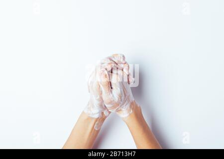 Grundlegende Hygieneverfahren zum Schutz vor Virusinfektionen. Weibliche Hände waschen mit Seife, Ansicht von oben auf weißem Hintergrund. Stockfoto