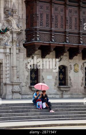 Auf der Treppe vor dem Rathaus von Lima Peru mit Regenschirm sitzen Stockfoto