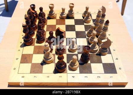 Gelbes und braunes Foto mit einem Bild von Schachbrettstücken, Holzstücken auf einem Schachbrett und Emtytisch . So spielen Sie Holzschach. Schach Stockfoto