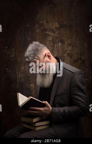 Porträt eines grauhaarigen bärtigen Mannes mit Brille Lesebuch auf Russisch, auf dem Cover russische Aufschrift M. Gorky, selektiver Fokus Stockfoto