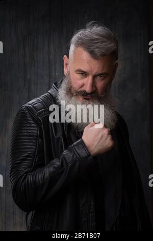 Studio-Porträt eines hübschen, reifen grauhaarigen bärtigen Mannes in einer Lederjacke, selektiver Fokus Stockfoto