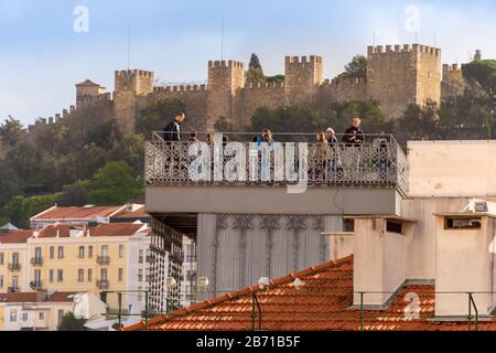 Lissabon, Portugal - 2. März 2020: Touristen locken beim Blick vom Elevador de Santa Justa. Schloss Lissabon Sao Jorge im Hintergrund. Stockfoto