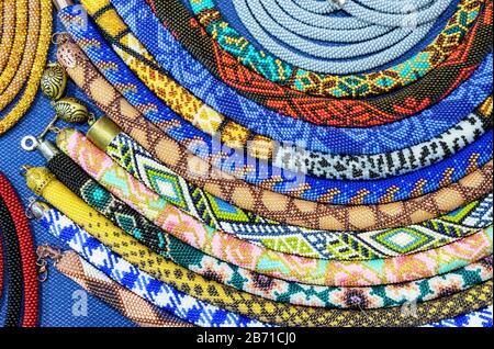 Ethnische Perlen mit verschiedenen Verzierungen werden mit der Technik des Webens mit Perlen hergestellt. Stockfoto