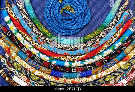 Ethnische Perlen mit verschiedenen Verzierungen werden mit der Technik des Webens mit Perlen hergestellt. Stockfoto