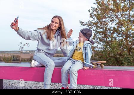 Junge Familie, Mama, selfie auf Smartphone, Sohn Junge Telefon, Sommerstadt. Glücklich lächelnd, Videoanruf aufzeichnen, Online-Anwendung im Internet Stockfoto