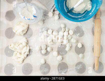 Rohe Knödel auf einem Holzbrett. Traditionelle hausgemachte Speisen. Der Prozess der Herstellung von Knödel. Slavisches traditionelles Gericht. Teig für Knödel. Mehl. Anzeigen Stockfoto