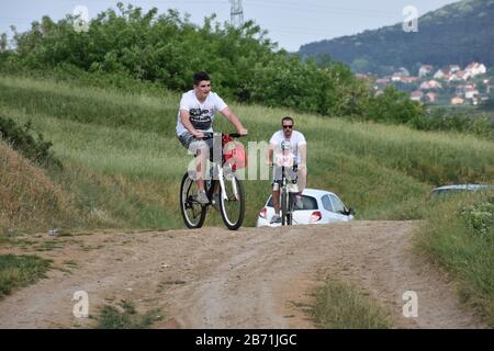 Mann und kleines Mädchen auf einem Fahrrad, älterer Junge auf einem anderen Fahrrad. Fahrradfahren in natürlicher Umgebung. Stockfoto