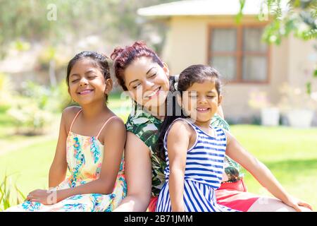 Liebe zwischen einer jungen Mutter und ihren beiden hübschen Töchtern im Freien Stockfoto