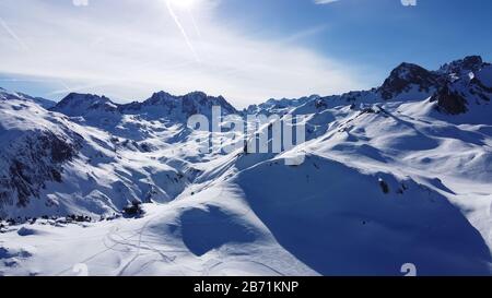 Luftbild der Alpen in Frankreich. Bergkuppen im Schnee bedeckt. Alpine Skianlagen von oben. Stockfoto