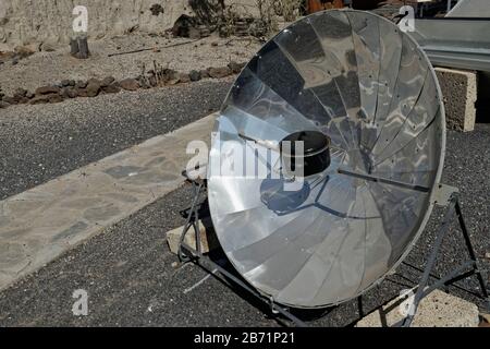 Solarkocher mit reflektierender Parabelform, die die Wärme der Sonne auf einen Kasserolenkopf aus Metall fokussiert, in einem Display mit erneuerbarer Energie auf dem ITER Biocli Stockfoto