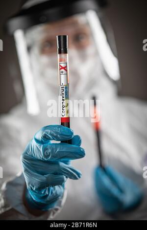 Laborarbeiterin hält Reagenzglas mit Blutmarkierung Coronavirus COVID-19-Krankheit. Stockfoto