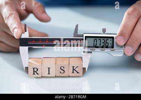 Nahaufnahme einer Person Hand messen Holz- risiko Bausteine mit digitalen elektronischen Messschieber Stockfoto