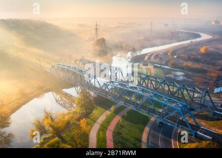Luftbild von Eisenbahnbrücke und Fluss bei Sonnenaufgang im Nebel Stockfoto
