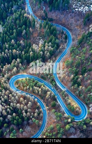 Der Luftbild der kurvenreichen Straße vom hohen Gebirgspass mit Bäumen in Siebenbürgen, Rumänien, in der Herbst-Winter-Zeit geschwungene Straßenansicht per Drohne Stockfoto