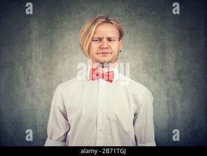 Der Mann ärgerte sich verärgert grimacing mit Abscheu sein Gesicht isoliert auf grauem Hintergrund. Stockfoto