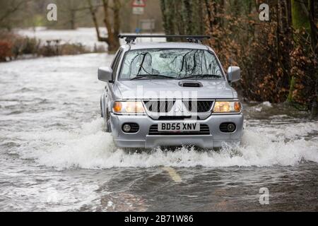 Überschwemmungen durch Storm Ciara an der Rothay Bridge in Ambleside, Lake District, Großbritannien, mit Autos durch die Überschwemmungen. Stockfoto