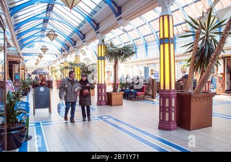 Mann und Frau, die durch die gläsernen Eingangshalle im Foyer zum Winter Gardens Complex Blackpool Lancashire England Großbritannien spazieren Stockfoto